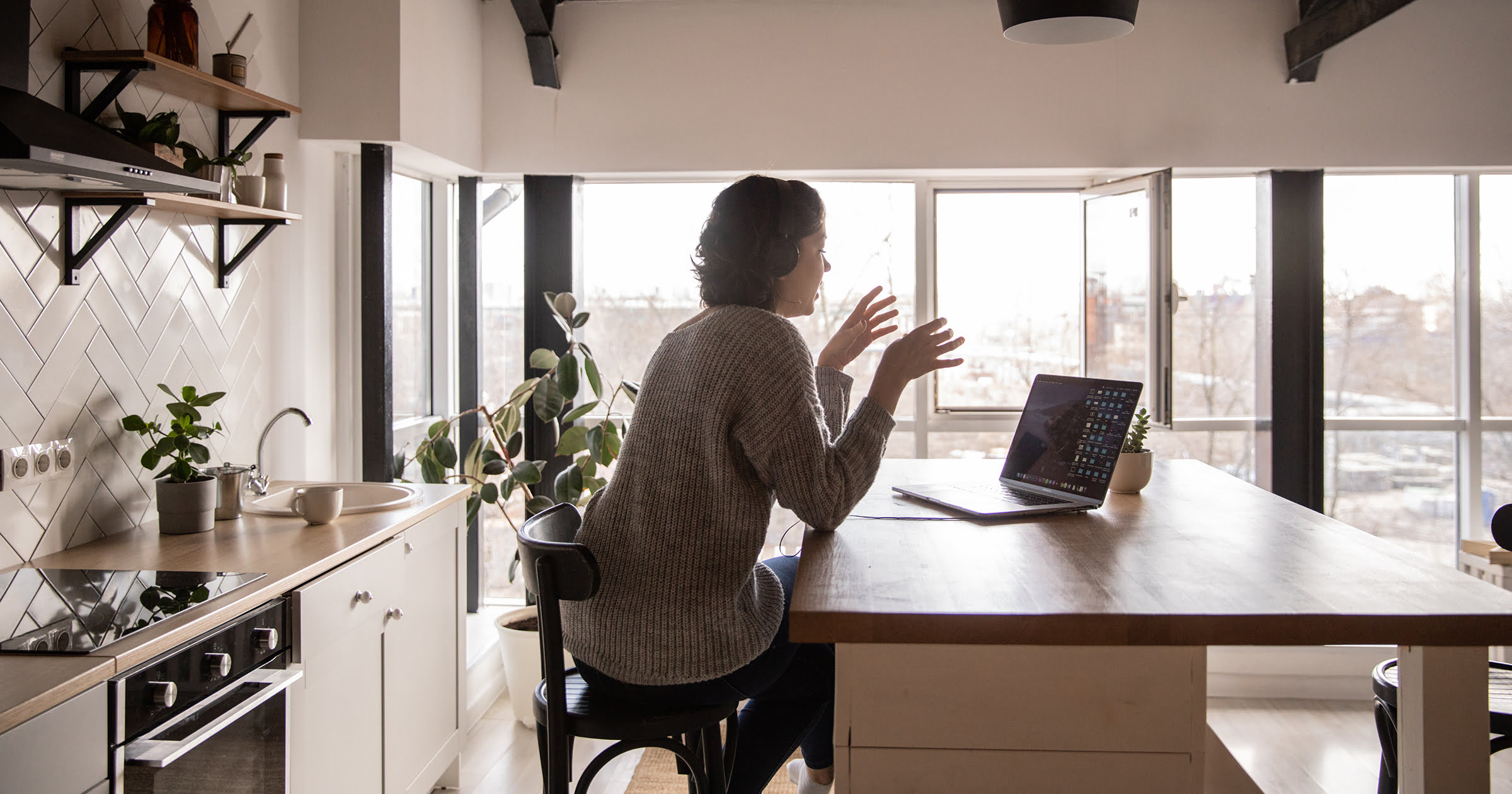 woman sitting in modern kitchen with several windows