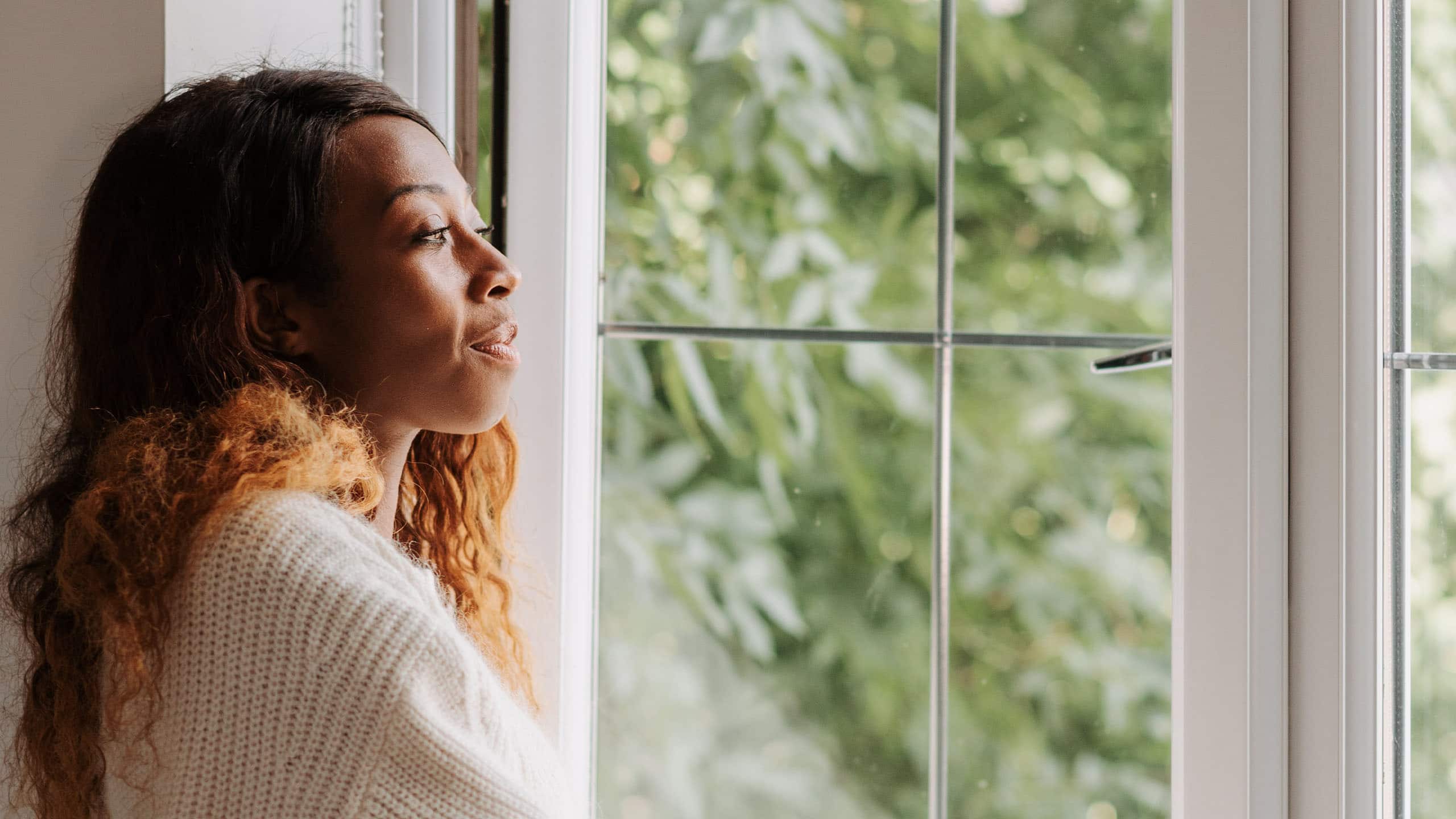 young black woman looking out her window