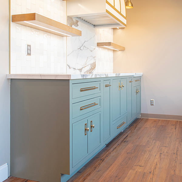 kitchen cabinets with wood floating shelves and hood vent