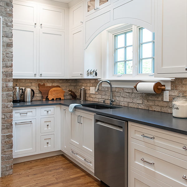 kitchen sink with dark countertops and white cabinets