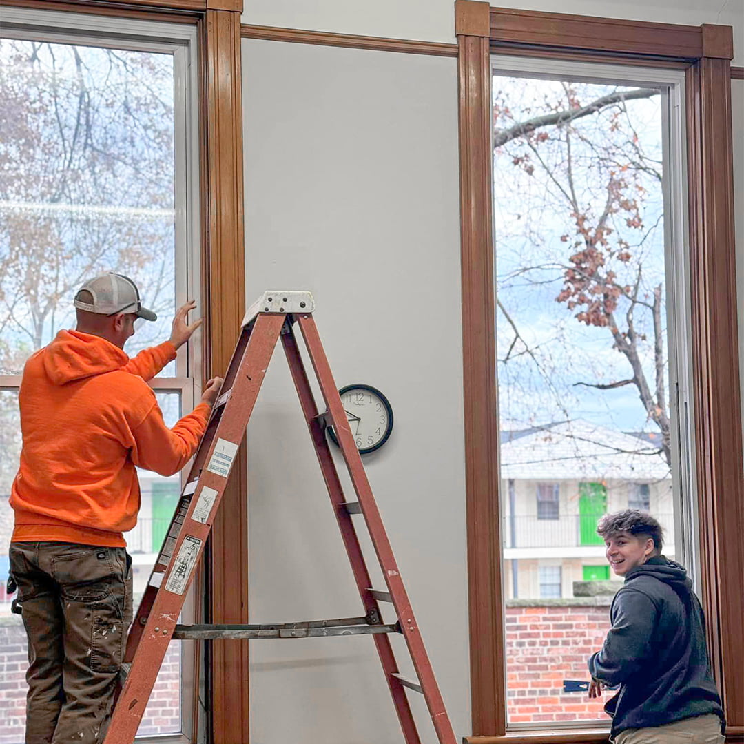 two skilled construction workers replacing tall windows in old office building