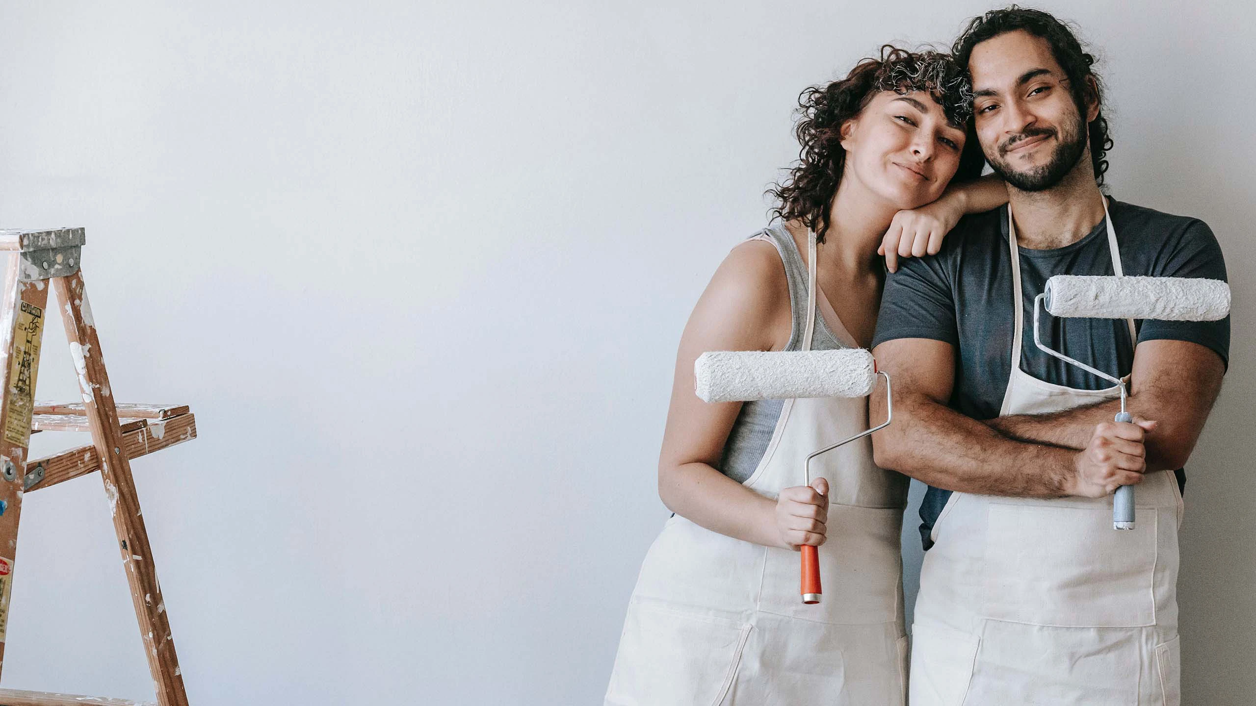 young couple smiling holding paint rollers during kitchen remodel