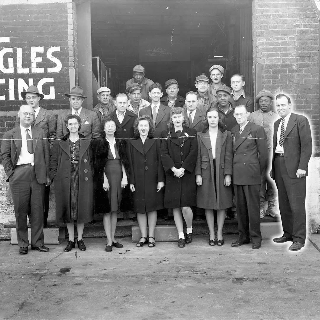 group of working adults in the 1940s standing in front of a warehouse