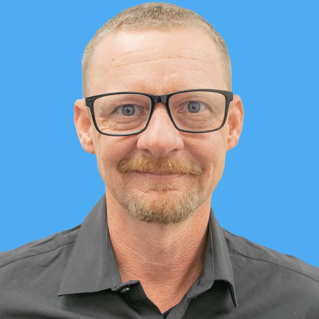 adult male with short brown hair and black rimmed glasses wearing a collared shirt