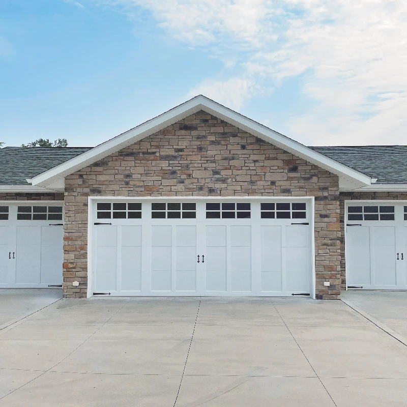 wide white garage door on stone home